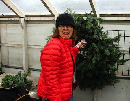 A woman makes a disgusted face and points to a messy wreath.