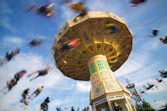 People sitting on swings are spun high in the air.