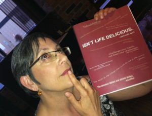 A woman holds up a booklet and puts a finger to her chin, deep in thought.