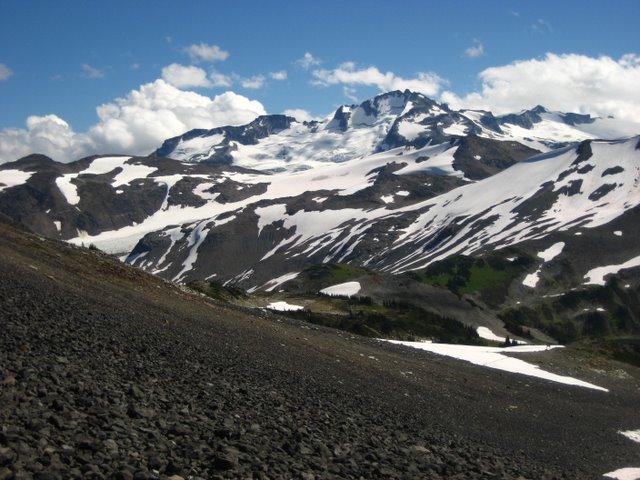 A large mountain with bare rock showing through the snow.