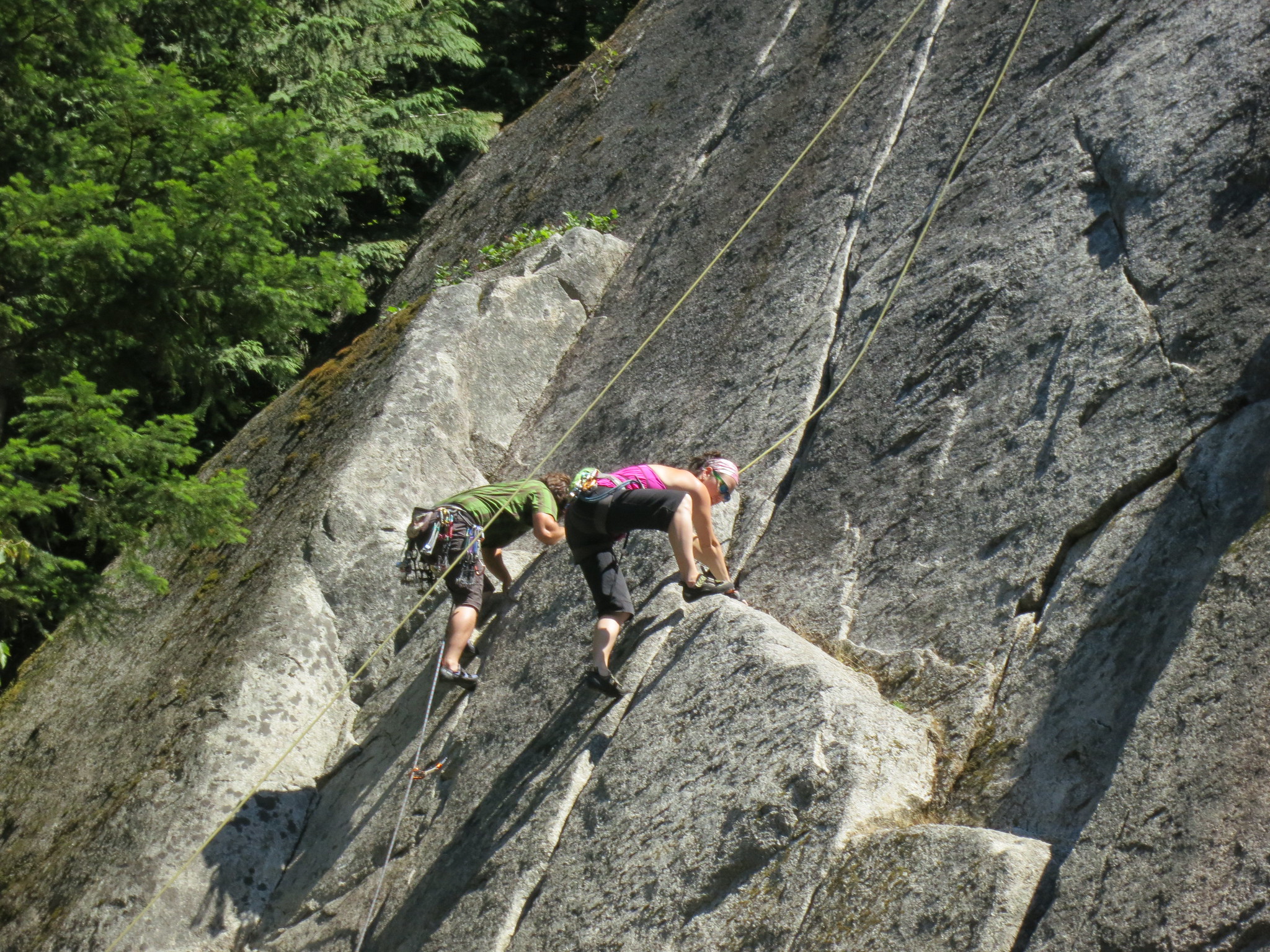 Two people climb a rock face.