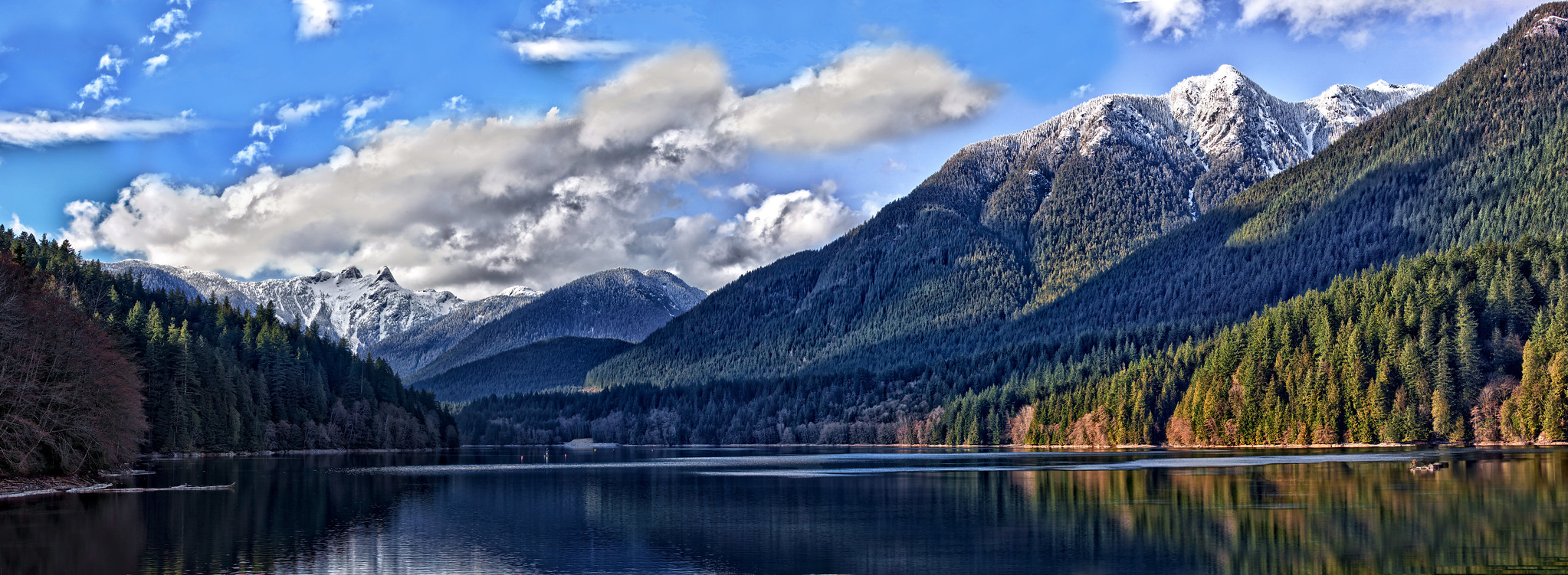 A smooth lake with mountains rising up in the background.