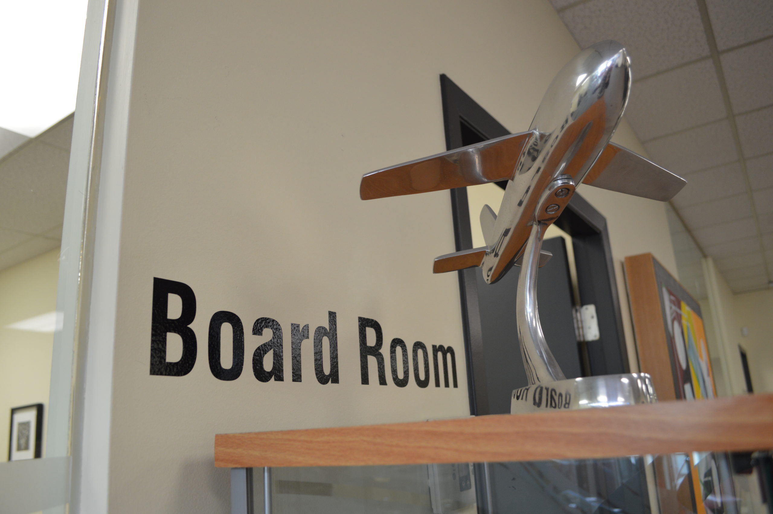 A small airplane statue outside the doorway to a boardroom.