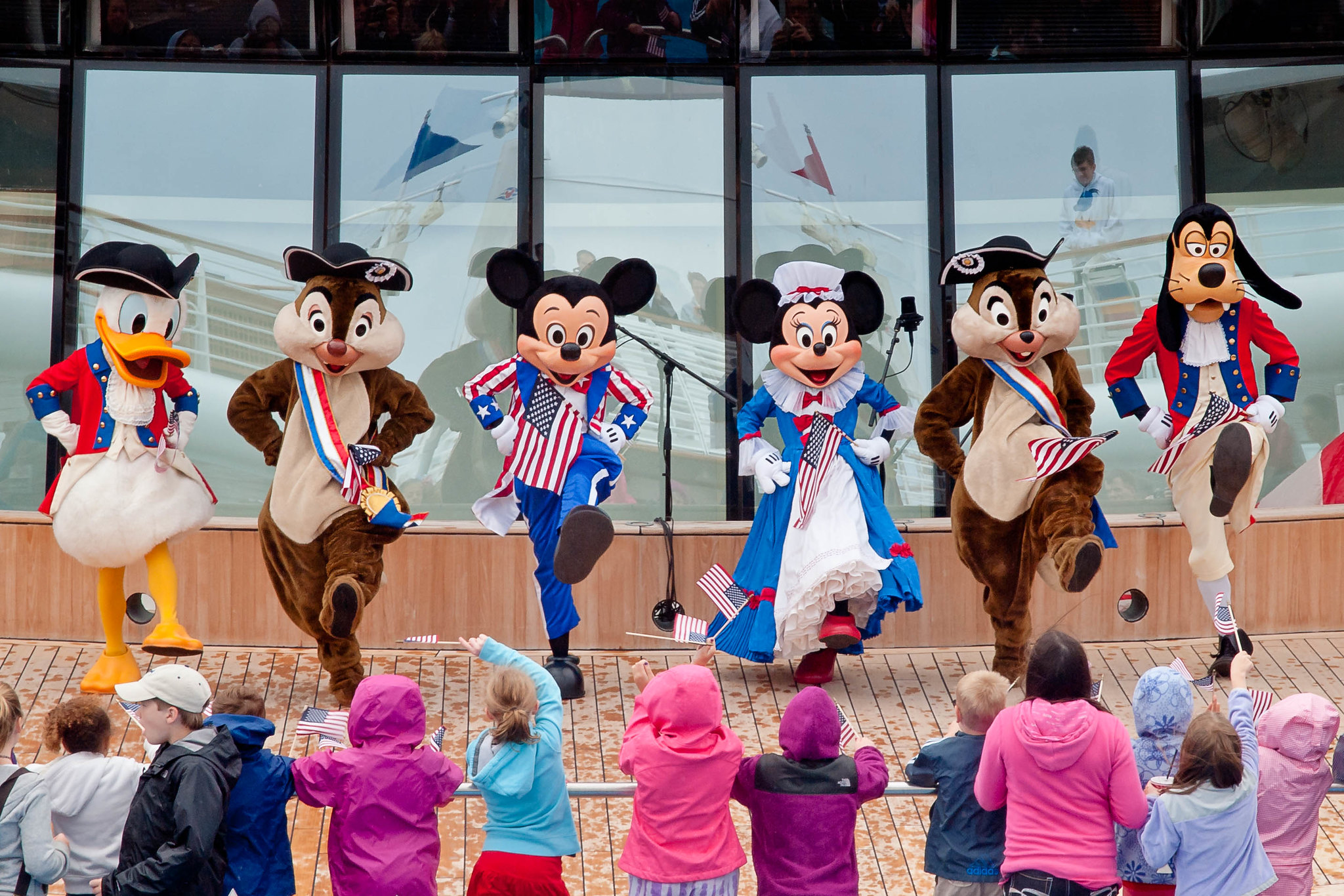 People dressed in classic Disney character costumes perform for a crowd of children.