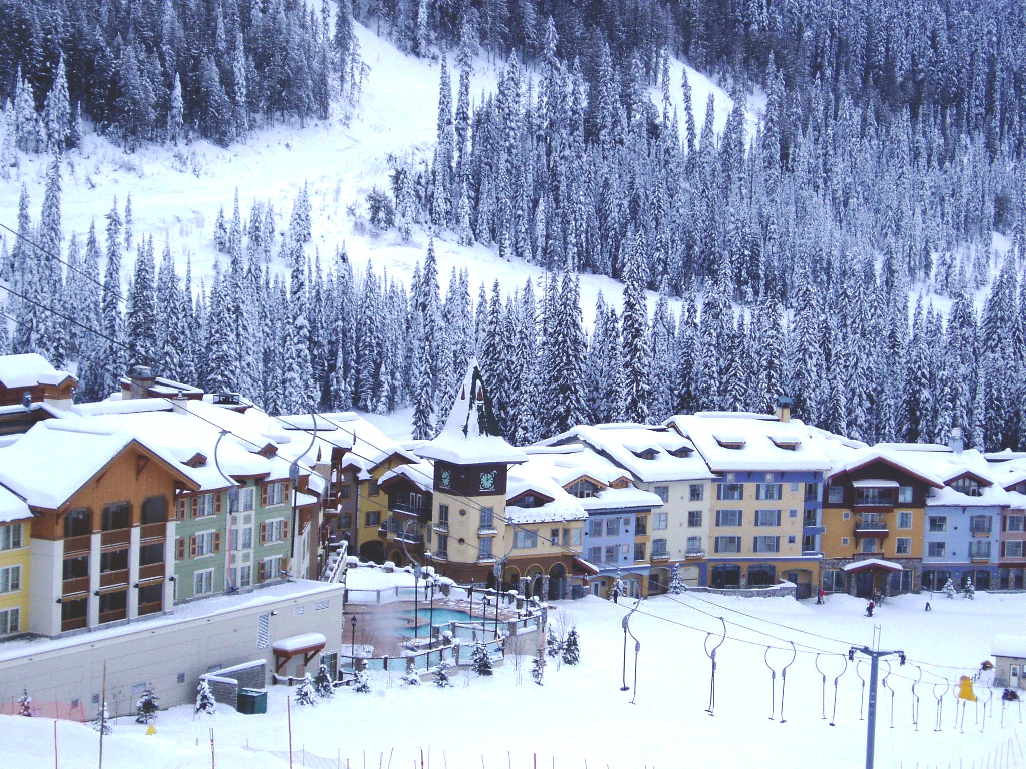 A large hotel at the bottom of a ski hill in winter.