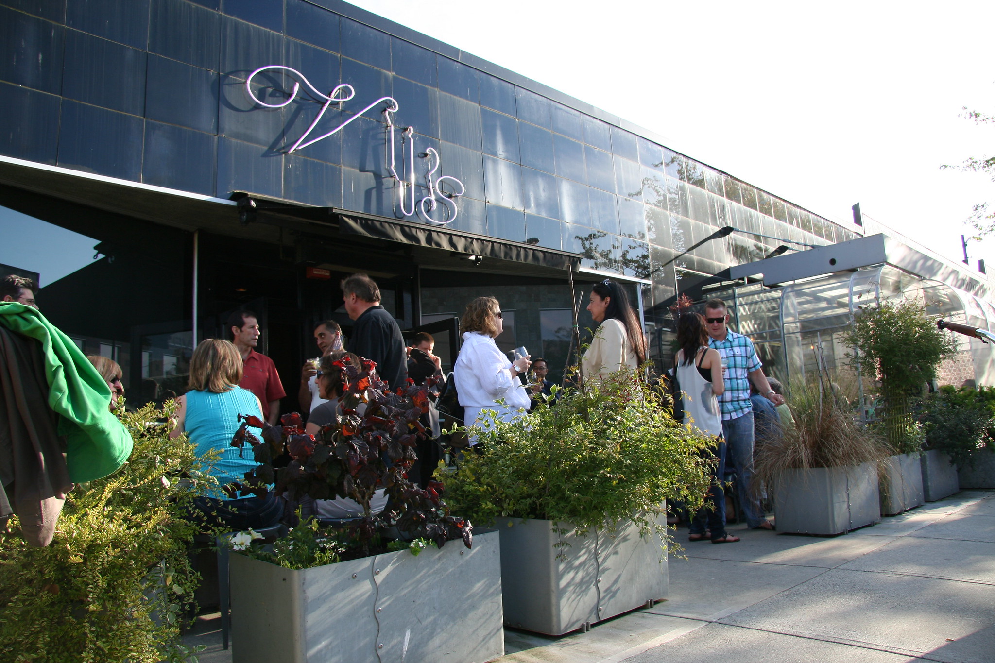 Many people line up outside a chic modern restaurant.