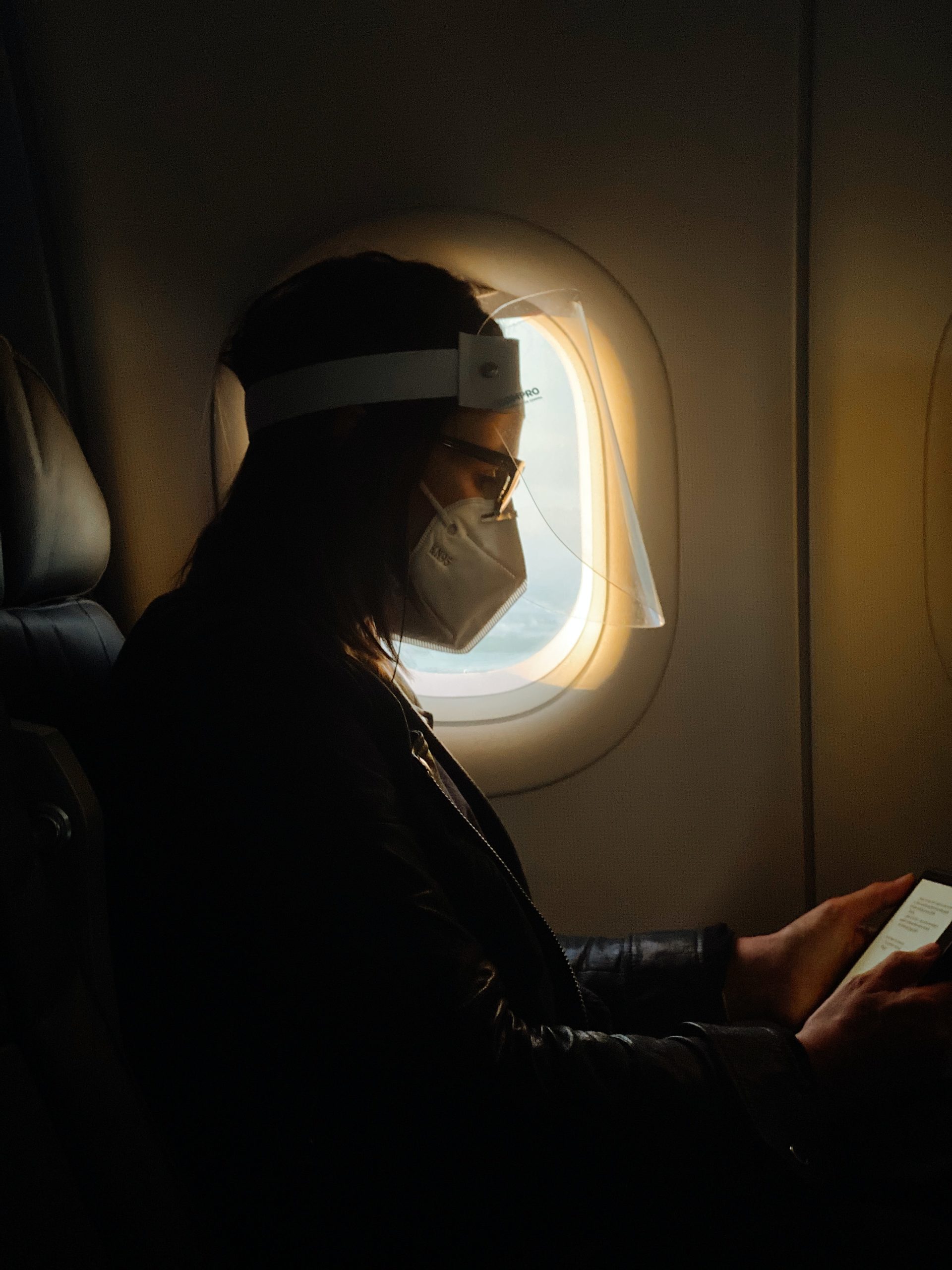 A plane passenger wears a face mask and a face shield.