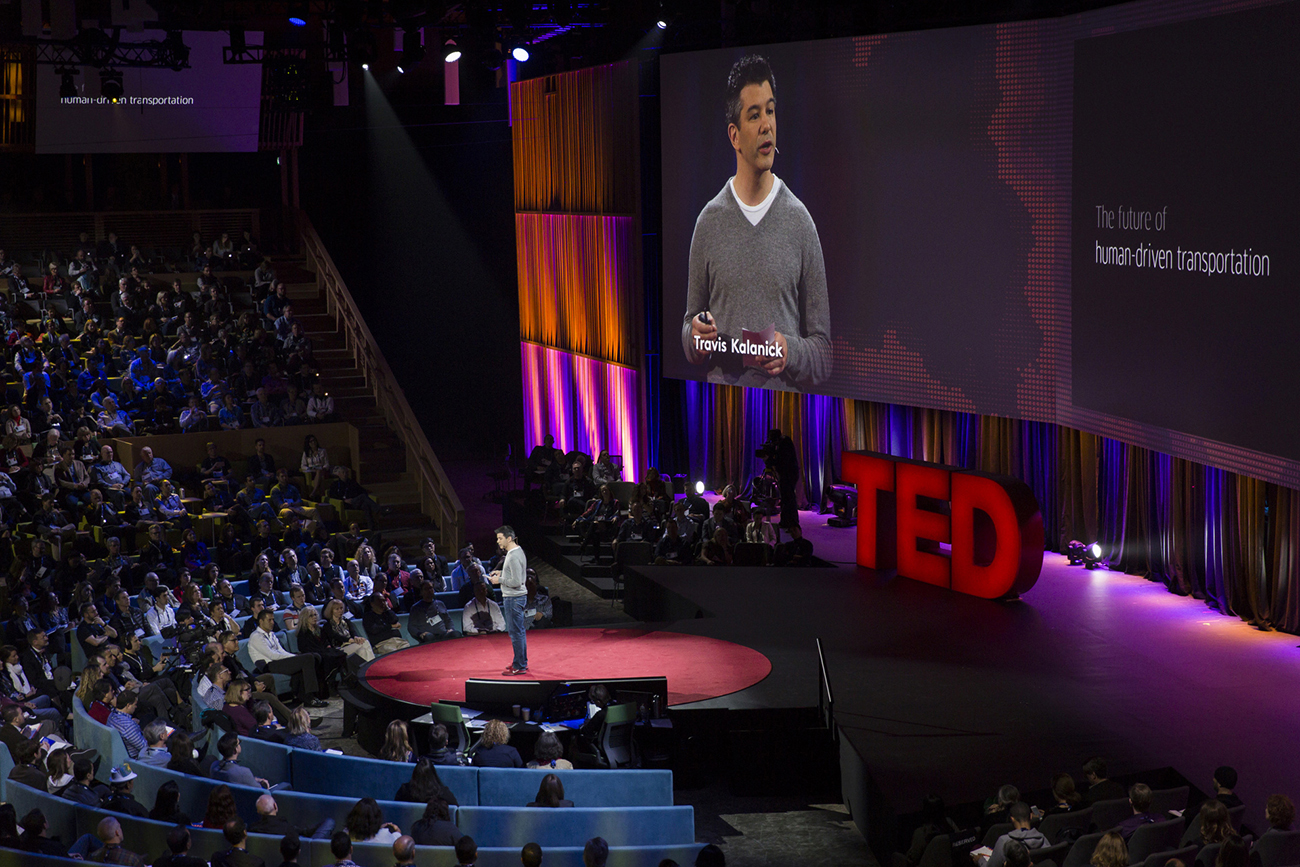 A photo shows Travis Kalanick talking to a large audience during a TED talk.