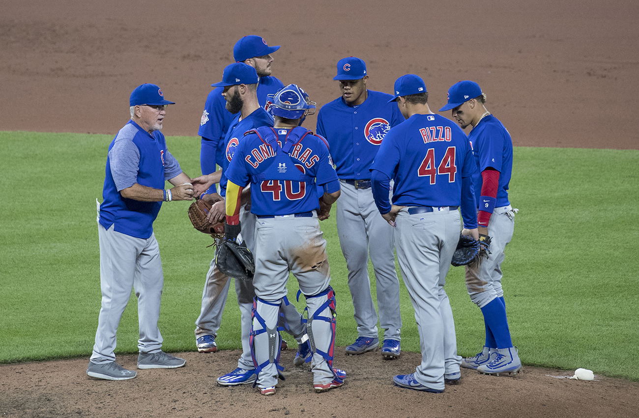 A photo shows Joe Madden, manager of the Chicago Cubs baseball team at pitcher mound, talking to the team.