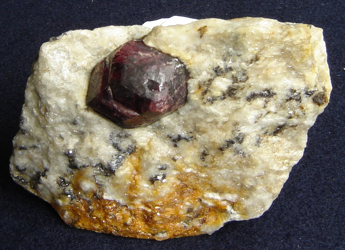 A dark red garnet embedded in a rock