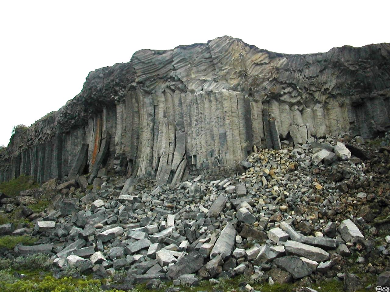 A cliff of basaltic columns with broken columns at the base.