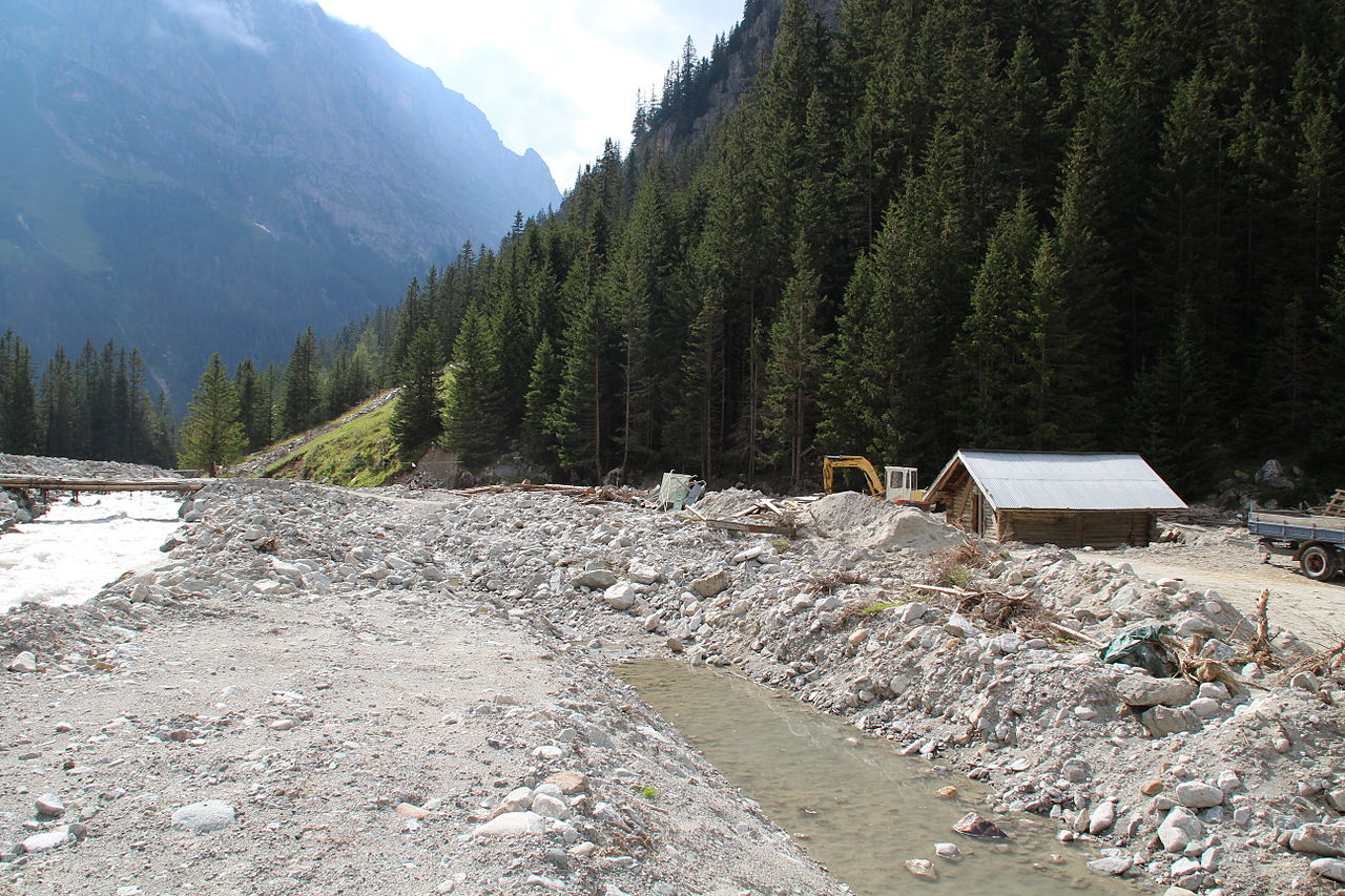 A deep valley is strewn with a thick layer coarse and fine-grained debris.