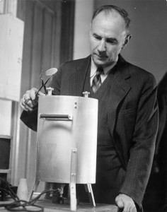 A man in a suit stands next to laboratory equipment.