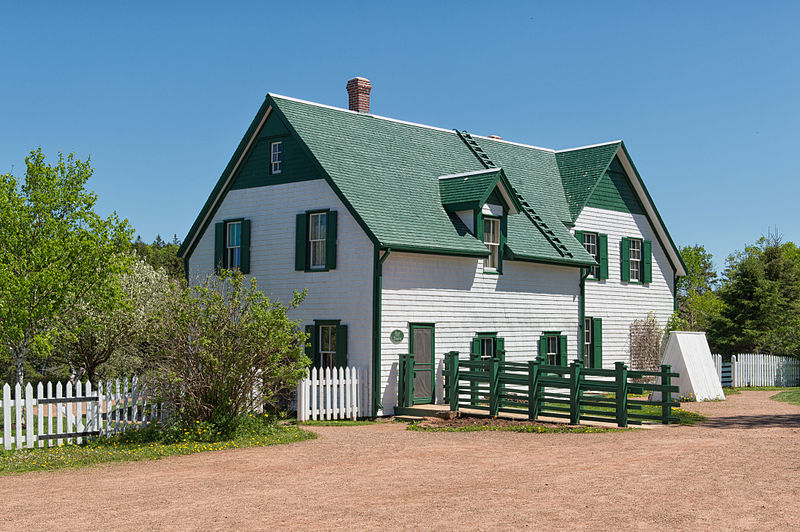 White farmhouse with a green roof and shutters.