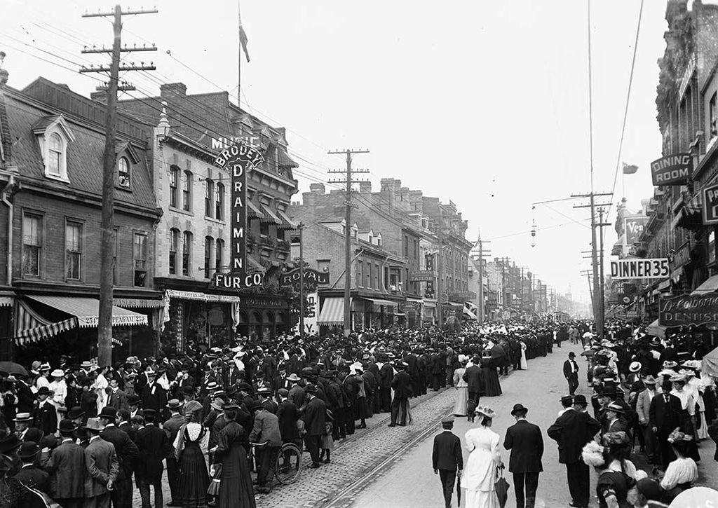 A city street packed with people at the turn of the century.