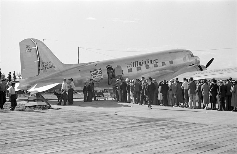 A line of passengers wait to board a small airplane.