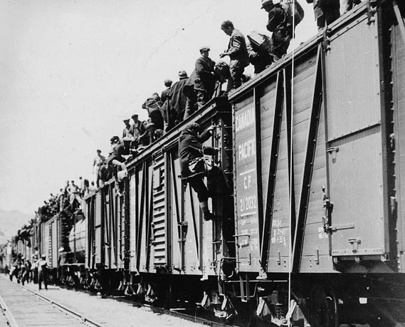 Men cover the roofs of boxcars.