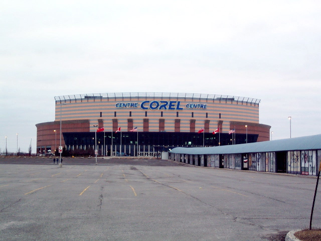 A hockey arena behind a parking lot.