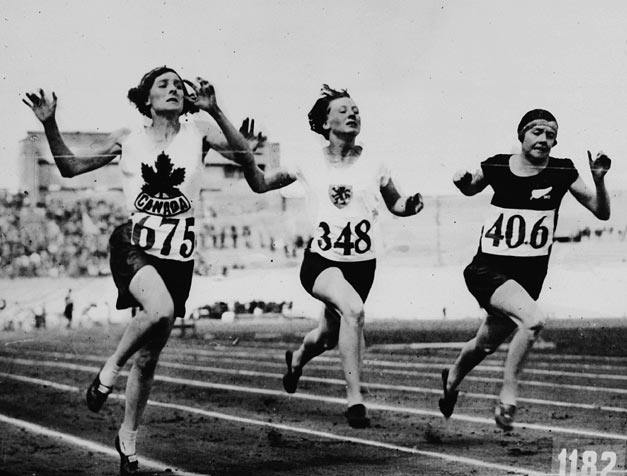 Three young women hurtle down a running track, arms raised, faces strained.