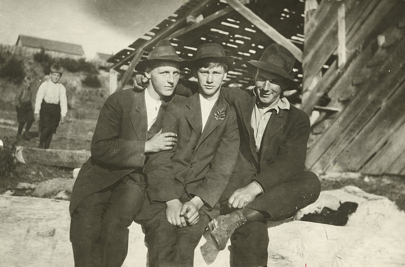 Three teenage boys in suits pose with their arms around each other.