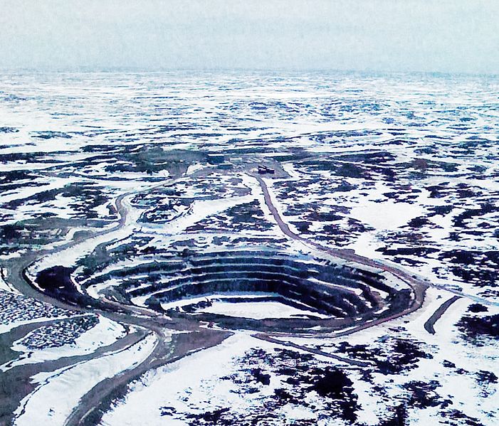 A small pit in a snow-covered field. Roads snake to and from the pit.