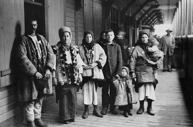 Three teenagers, two young children, and their parents at a train station.