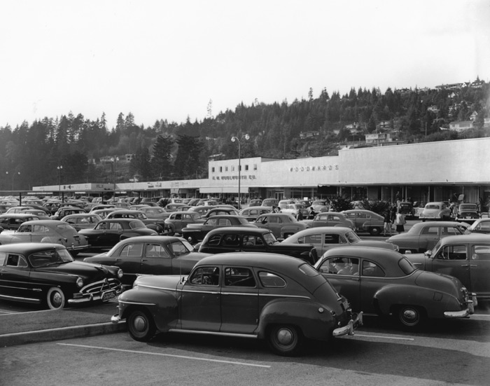 Cars crowd the parking lot of an early shopping mall.