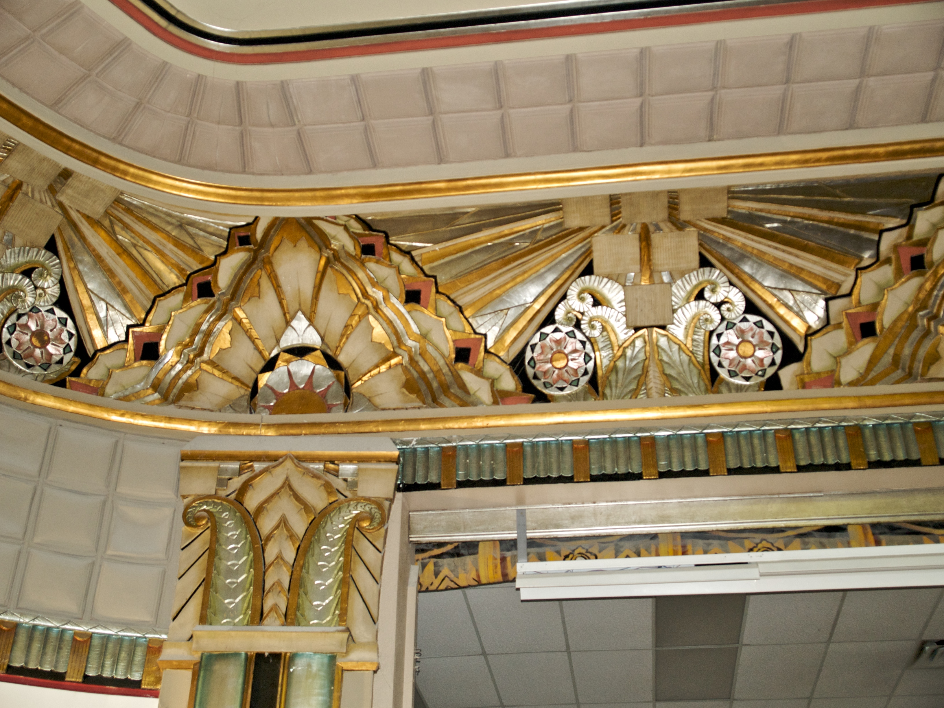 Ornate gold and silver leaf decorations in the ceiling of a building.