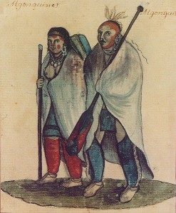 An aboriginal man and woman in loose clothing hold paddles and blankets around their shoulders