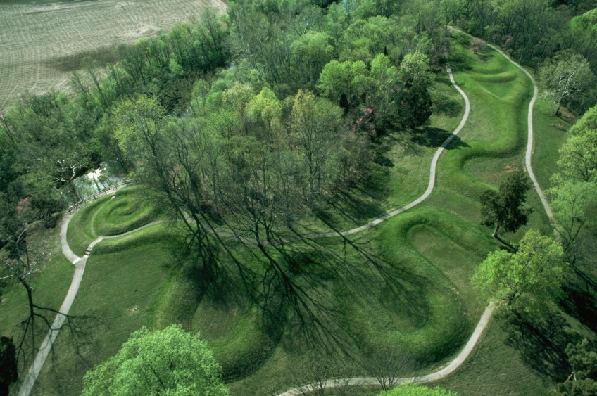 An aerial view of a winding manmade mound, shaped almost like a snake. Grass grows all over the mound.