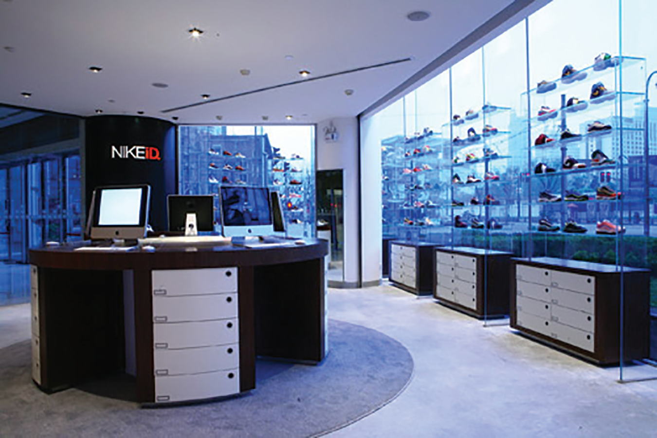 A picture of the inside of a NIKEiD store showing shoes on shelves by glass windows with a view of many tall buildings.