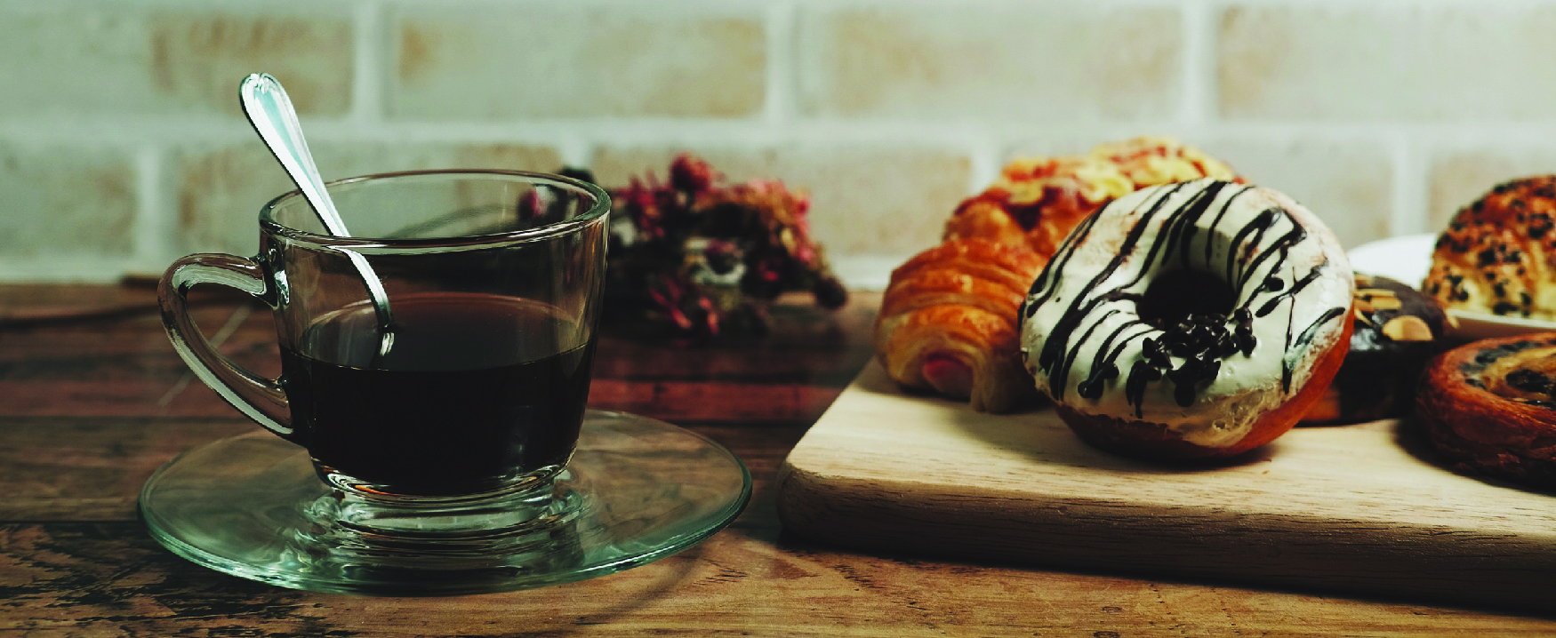 Picture of a cup of coffee beside a board with various pastries.