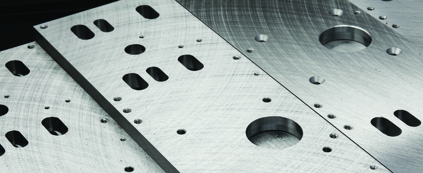 A picture of precision machined metal plates with many holes of differing sizes.