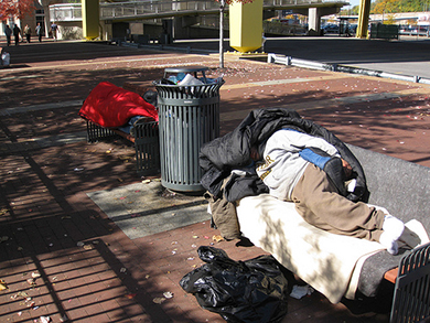 الاقتصاد / الصورة عبارة عن صورة لشخصين بلا مأوى وينامان على مقاعد مدينة عامة.