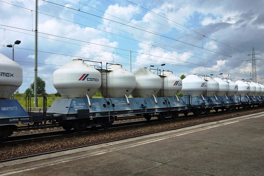 A photo shows the lateral view of a CEMEX’s freight train with cement tank wagons running along a railway track.