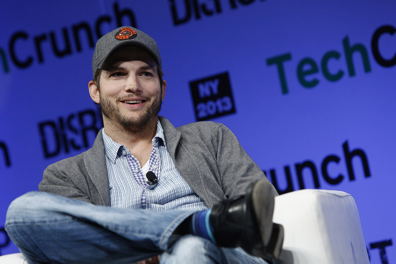 A photograph shows Ashton Kutcher sitting in front of a digital screen that reads Tech Crunch, N Y 2013.