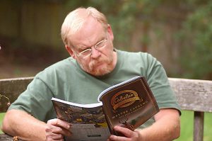 An man reading a Cabela's' catalog on a park bench.