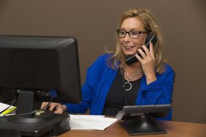 A woman sitting behind a desk talking on a phone.