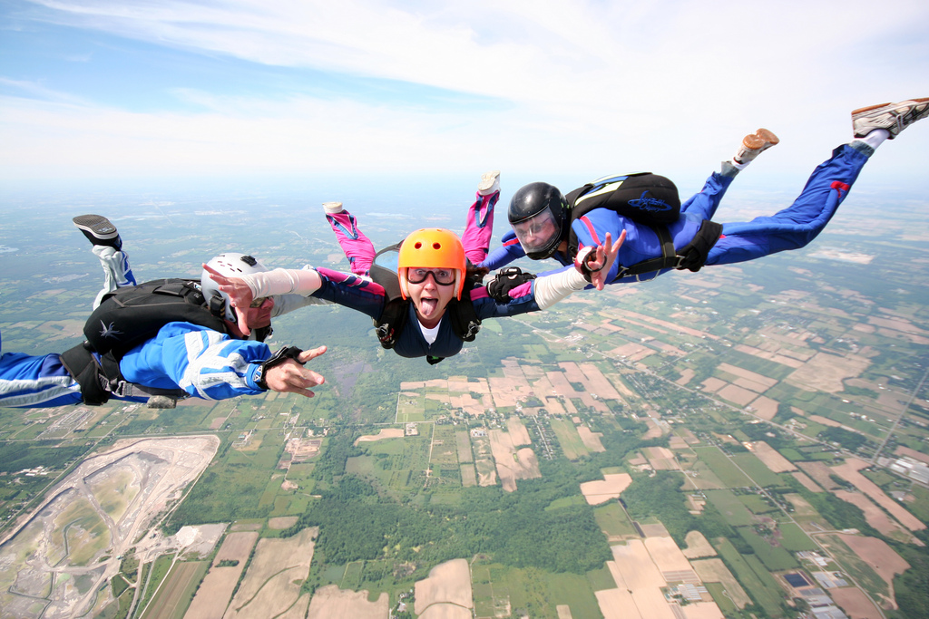 Three people falling through the air and making faces at the camera.