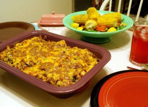 King Ranch Chicken casserole on a table with a bowl of mixed vegetables. All very tasty looking.