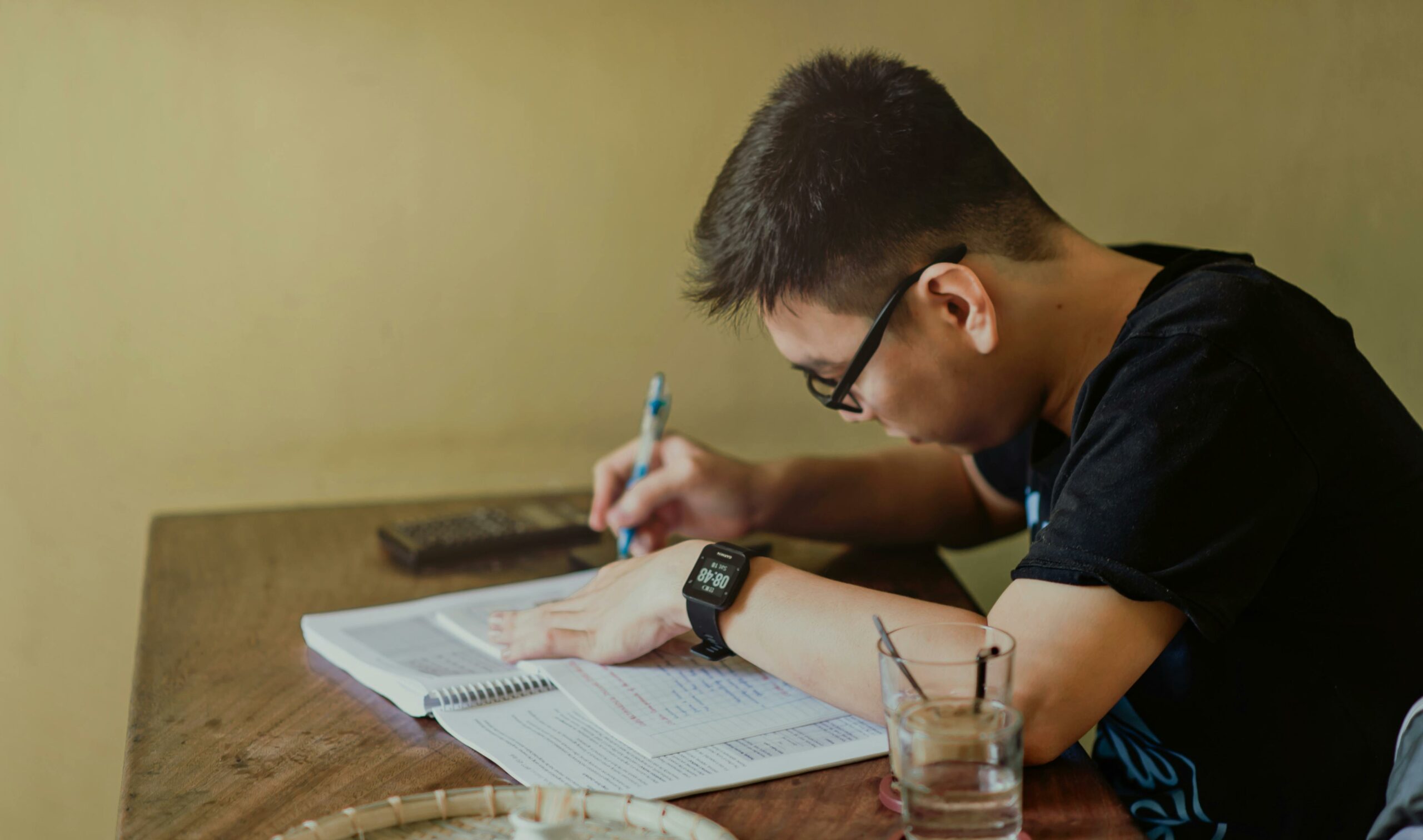 A person sitting at a desk, writing in a notebook.