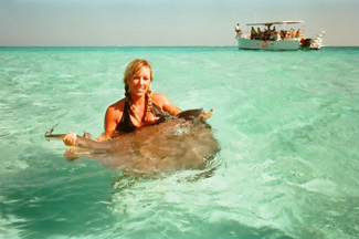 A photograph shows a woman standing in the ocean holding a stingray