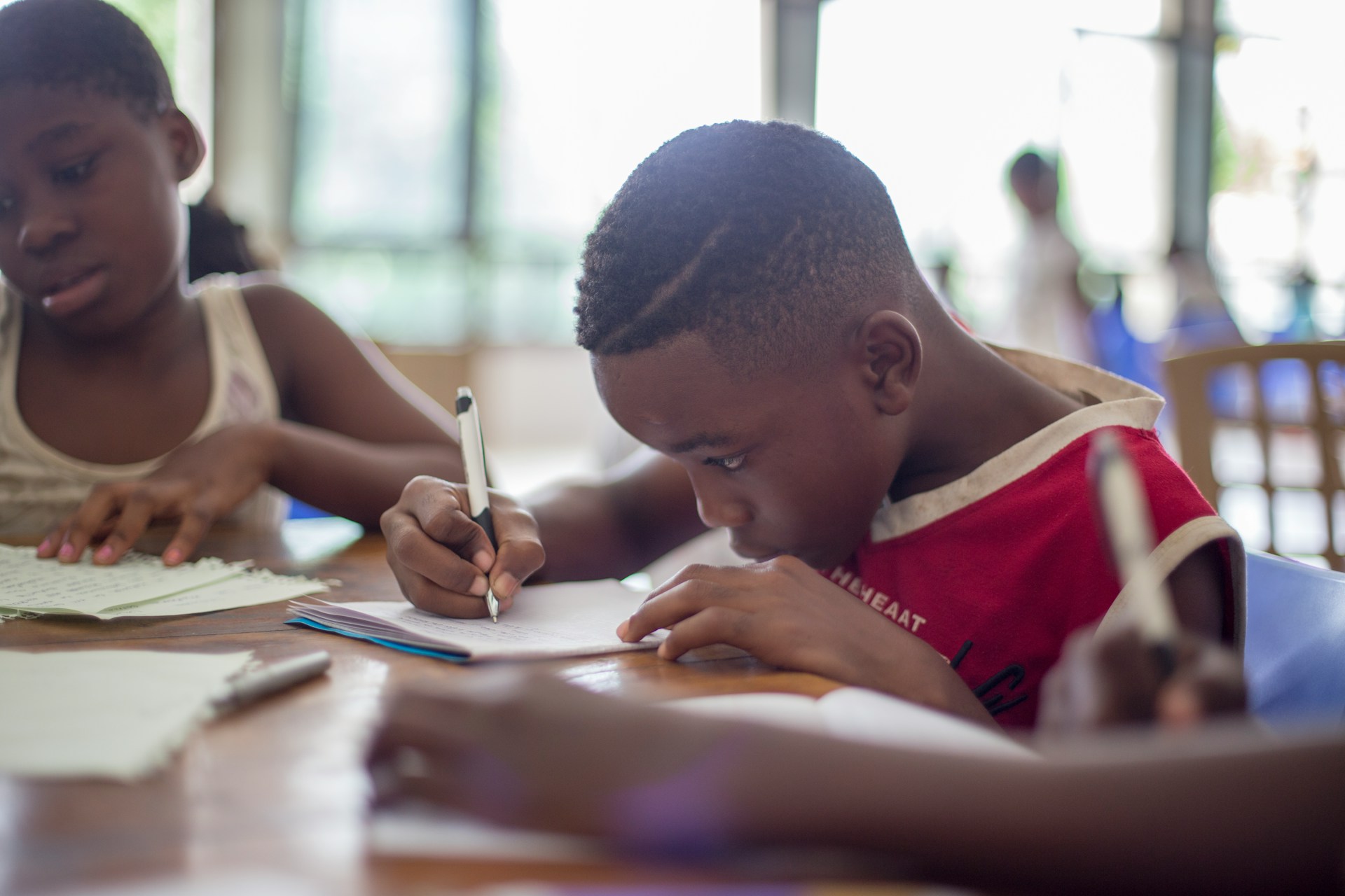 A child writing with a pen in a classroom.