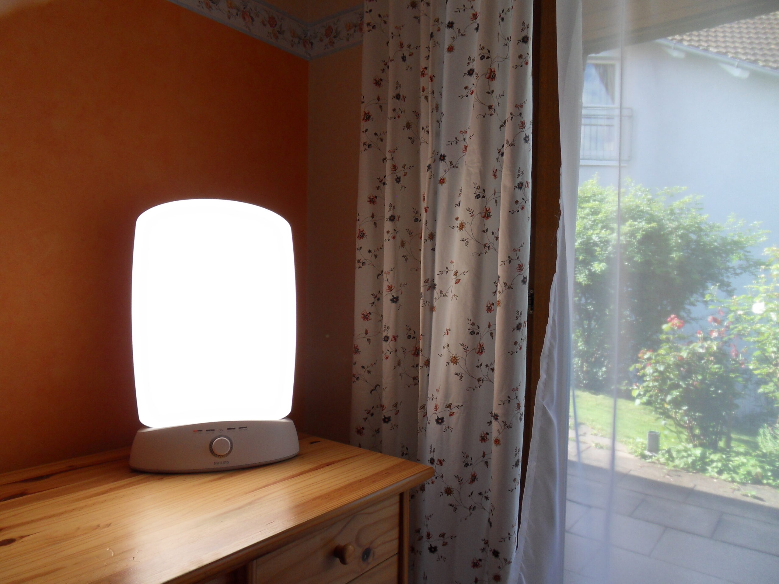 A bright therapy lamp sits on a dresser. 