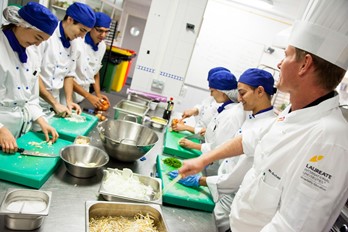 a chef training apprentices in the kitchen