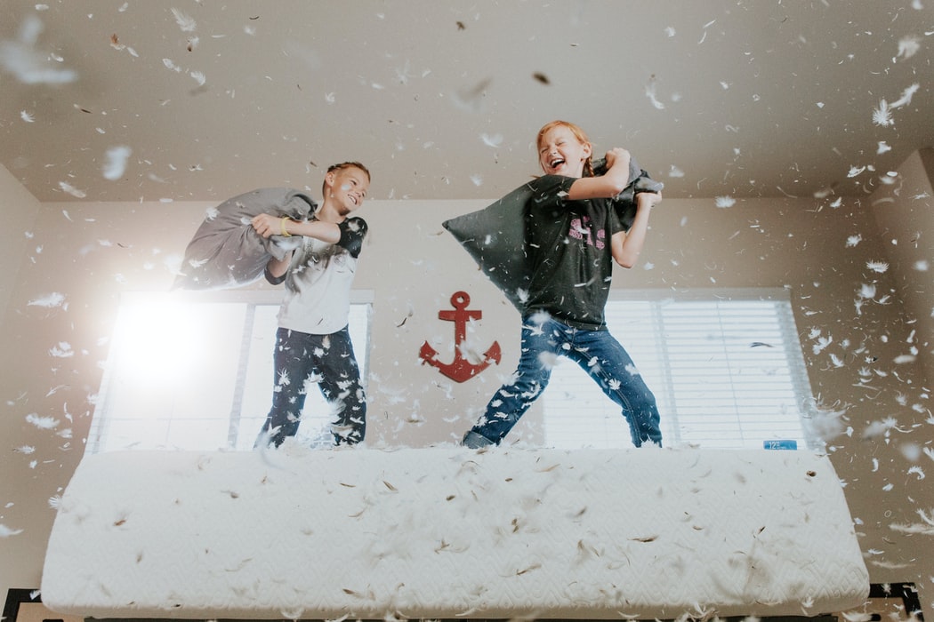 Two young kids in a pillow fight.