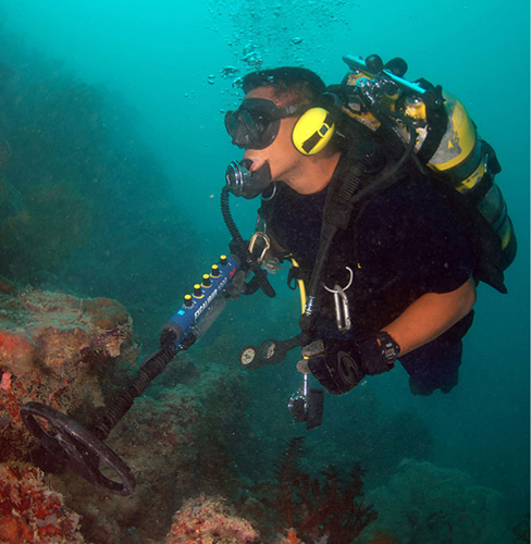 Photograph of an underwater diver using a metal detector.