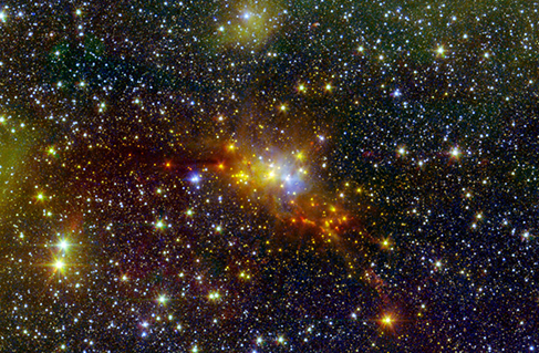 A telescope image showing numerous stars. A bright cluster in the center has yellow, orange and blue stars.