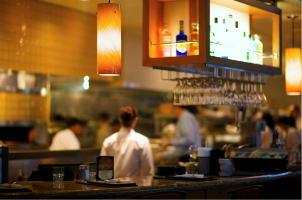 A restaurant bar with soft lighting and glasses hanging upside down above the counter.