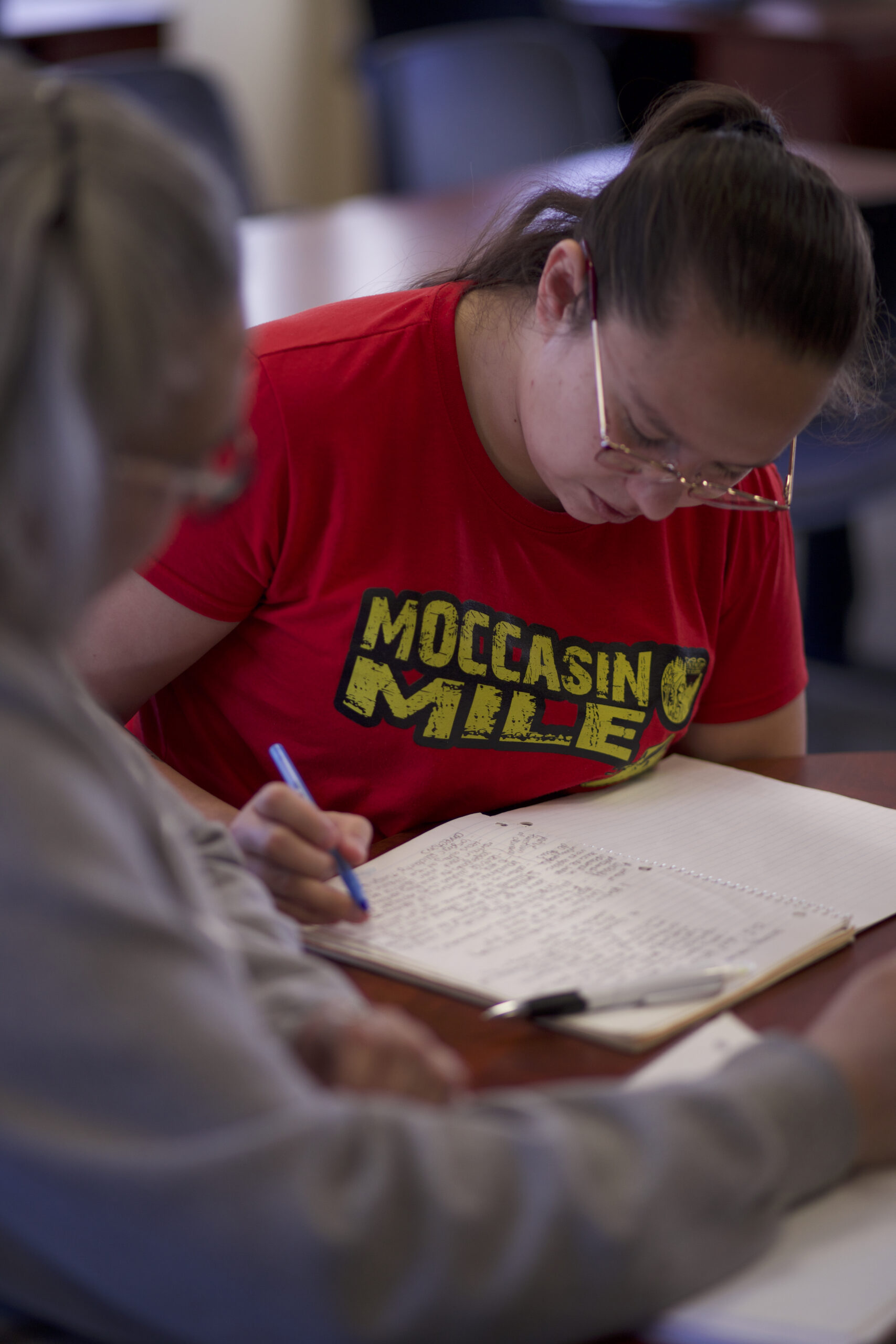 Indigenous students studying on campus. One writes in a journal.